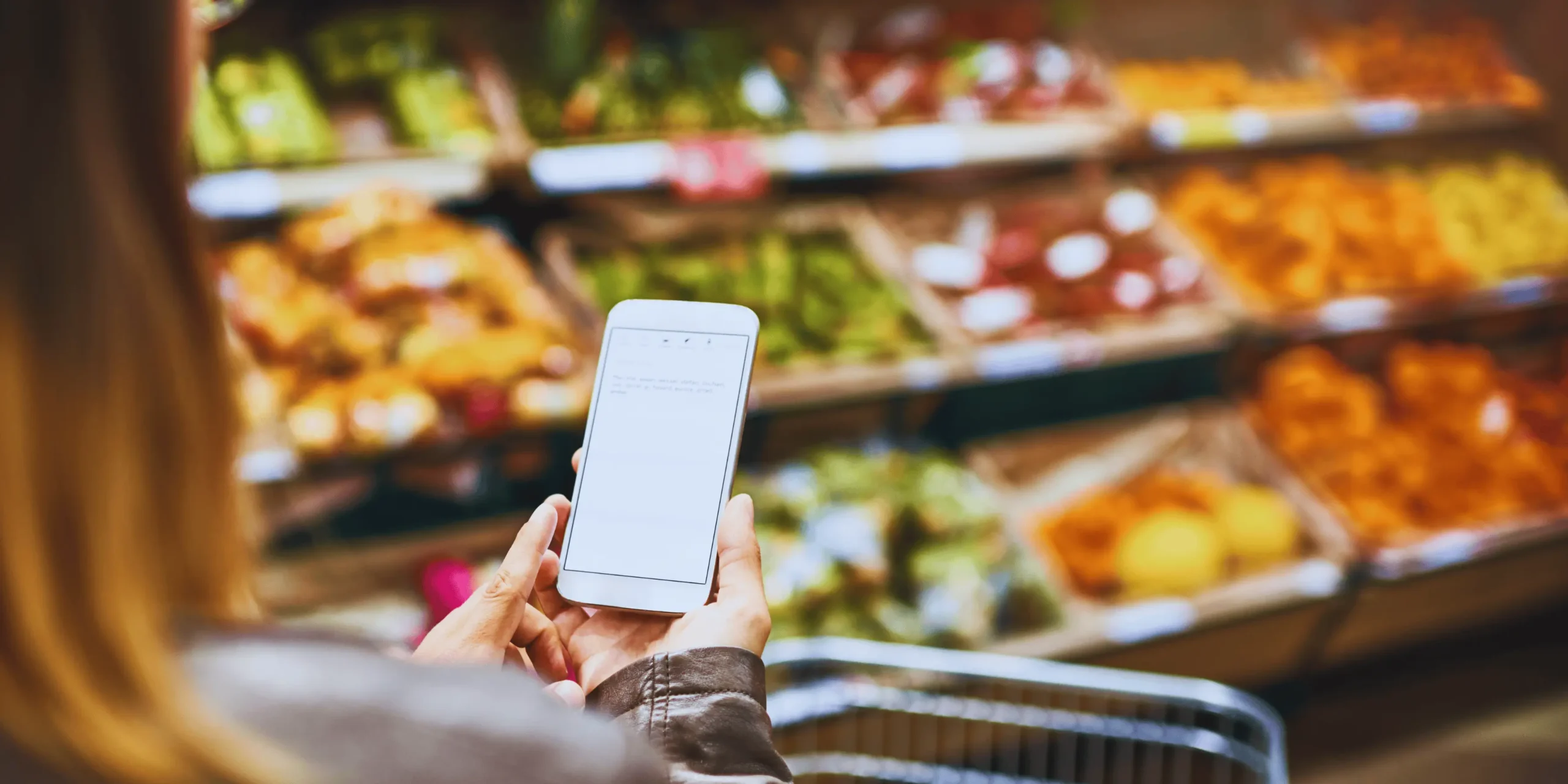 žena se dívá do mobilního telefonu při nakupování v obchodě